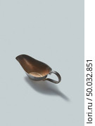 Bronze retro sauceboat with shadows on a white background, copy space. Vintage kitchenware.. Vintage retro steel empty gravy boat on a white background with shadows, place for text. Стоковое фото, агентство Ingram Publishing / Фотобанк Лори