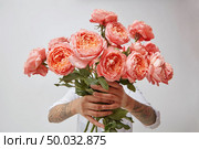 Amazing bouquet of freshly picked roses a color of the year 2019 Living Coral Pantone in a girl’s hands with tatoo on a white background. Concept for Valentine’s day or Mother’s day.. Young girl’s hands is holding a bouquet of fresh flowers in her hands with tatoo in a color of the year 2019 Living Coral Pantone. Стоковое фото, агентство Ingram Publishing / Фотобанк Лори