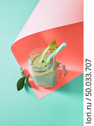 Organic freshly picked vegetables mixing healthy vegetarian smoothie in a glass mason jar on a color background of the year 2019 Living Coral Pantone, copy space. Flat lay.. Homemade fresh smoothies with avocado, selery, cucumber on a color background of the year 2019 Living Coral Pantone, copy space. Flat lay. Стоковое фото, агентство Ingram Publishing / Фотобанк Лори