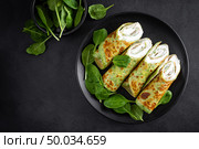 Savory crepes with spinach and feta cheese on black background, top view. Стоковое фото, агентство Ingram Publishing / Фотобанк Лори