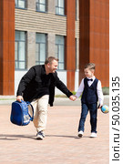 Dad walking hand in hand with his son from school. Father takes the boy from lessons. Parental care, return to school, education. The first day of school. Father Day. Стоковое фото, фотограф Ирина Михайличенко / Фотобанк Лори