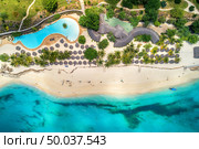 Aerial view of tropical sandy beach with palms and umbrellas at sunny day. Summer holiday on Indian Ocean, Zanzibar, Africa. Landscape with palm trees, hotels, pool, white sand, azure sea. Top view. Стоковое фото, агентство Ingram Publishing / Фотобанк Лори