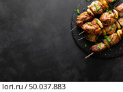 Grilled meat skewers, shish kebab on black background, top view. Стоковое фото, агентство Ingram Publishing / Фотобанк Лори