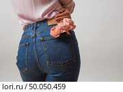 Perfect woman’s bottom in a blue jeans and fresh roses living coral color in a back pocket on a light gray background, place for text. Concept of Woman’s or Mother’s Day.. Attractive woman’s butt in a blue jeans and fresh roses living coral color in a back pocket on a light gray background, place for text. Congratulation card. Стоковое фото, агентство Ingram Publishing / Фотобанк Лори