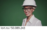 Confident female engineer smiling in protective gear on green background. Стоковое AI-видео, аниматор Владимир Федоров / Фотобанк Лори