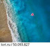 Aerial view of young woman swimming on the pink swim ring in the transparent turquoise sea in Oludeniz,Turkey. Summer seascape with girl, beautiful waves, blue water in sunny day. Top view from drone. Aerial view of young woman swimming on the pink swim ring. Стоковое фото, агентство Ingram Publishing / Фотобанк Лори