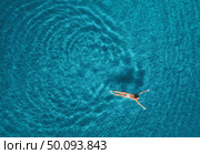 Aerial view of swimming woman in Blue Lagoon. Mediterranean sea in Oludeniz, Turkey. Summer seascape with girl, clear azure water, waves in sunny day. Transparent water. Top view from flying drone. Aerial view of swimming woman in mediterranean sea. Стоковое фото, агентство Ingram Publishing / Фотобанк Лори