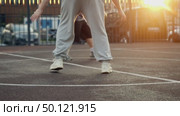 A young and agile teenager easily outwits his older brother while playing basketball at a park in the city at sunset. Стоковое видео, видеограф Strunov David / Фотобанк Лори