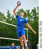 A man in a blue shirt and blue shorts is jumping to hit a volleyball. Стоковое AI-изображение, AI-художник Ярославский Максим / Фотобанк Лори