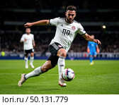 A soccer player in a white and black uniform kicks a soccer ball on a field. Стоковое AI-изображение, AI-художник Ярославский Максим / Фотобанк Лори