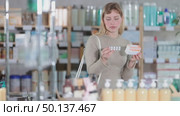 Selective young woman customer choosing needed pills in box in chemistry in cold season. Стоковое видео, видеограф Яков Филимонов / Фотобанк Лори