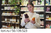 Woman chooses natural fruit juice in a store with organic products. European woman buys juices in eco supermarket. Customer reads the labels with the ingredients of sugar-free juice. Стоковое видео, видеограф Яков Филимонов / Фотобанк Лори