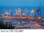 Sea commercial port at night in Mariupol, Ukraine. Industrial view. Cargo freight ship with working cranes bridge in sea port at twilight. Cargo port, logistic. Стоковое фото, агентство Ingram Publishing / Фотобанк Лори