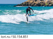 A middle aged man doing some foil surfing or hydrofoil surfing in the sea on a bright sunny day. Стоковое фото, агентство Ingram Publishing / Фотобанк Лори