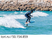 A middle aged man doing some foil surfing or hydrofoil surfing in the sea on a bright sunny day. Стоковое фото, агентство Ingram Publishing / Фотобанк Лори