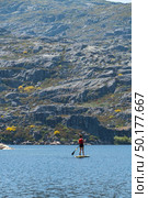 Stand up paddleboarding on lake. Watersport on lake. Tourist outdoor activity at Lagoa Comprida, Serra da Estrela National Park in Portugal. Стоковое фото, агентство Ingram Publishing / Фотобанк Лори