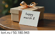 Gift box tied with ribbon and postcard for March 8 on the table. AI Generative. Стоковое AI-видео, аниматор Spirit River / Фотобанк Лори