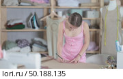 Young woman tailor drawing with pencil on brown paper, she sketching clothes and patterns on table in sewing workshop. Стоковое видео, видеограф Яков Филимонов / Фотобанк Лори