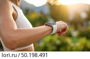 A close-up of a woman checking a smartwatch outdoors at sunset, representing fitness, technology, and active lifestyle trends. Стоковое AI-изображение, AI-художник Ольга Сухарева / Фотобанк Лори
