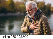 A man with a heart condition is standing by a body of water. Стоковое AI-изображение, AI-художник Ярославский Максим / Фотобанк Лори
