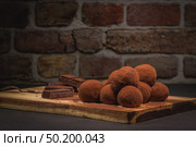 Craft chocolate truffles on wooden board with cocoa powder. Стоковое фото, агентство Ingram Publishing / Фотобанк Лори