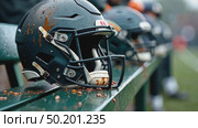 A close-up of a football player's mud streaked helmet resting on the bench, raindrops sliding down its surface, the blurred motion stadium arena background. Стоковое AI-видео, аниматор Sergey Grishin / Фотобанк Лори