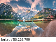 Amazing Braies lake at sunrise in autumn in Dolomites, Italy. Landscape with mountains, sky with clouds, boats, water with reflection, trees with colorful leaves. Lake in fall. Italian alps. Panorama. Amazing Braies lake at sunrise in autumn in Dolomites, Italy. Стоковое фото, агентство Ingram Publishing / Фотобанк Лори