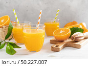Orange juice. Freshly squeezed juice in glasses and fresh fruits with leaves. Стоковое фото, агентство Ingram Publishing / Фотобанк Лори