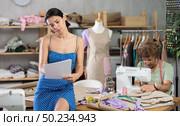 Young tailoress drawing sketches and man sewing in workshop. Стоковое фото, фотограф Яков Филимонов / Фотобанк Лори