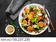 Christmas salad with boiled beet, red onion, tangerines, pomegranate, parsley, pine nuts and lettuce leaves. Стоковое фото, агентство Ingram Publishing / Фотобанк Лори