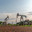Oil production at the field using two rocking machines. In the background is a drilling rig and equipment for drilling wells. Summer. Beautiful sky and nature. Стоковое фото, фотограф Владимир Ендовицкий / Фотобанк Лори