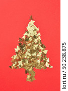 New Year creative decorative tree handmade frome shiny small spruces on a red background with place for text. Greeting holiday card.. Decorative Christmas composition from shiny spruces. Стоковое фото, агентство Ingram Publishing / Фотобанк Лори