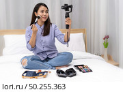 Young beautiful Asian woman beauty vlogger or blogger recording live how to make up tutorial to share on social media using Gimbal Stabilizer on mobile phone. Using for vlog social media influencer concept. Стоковое фото, агентство Ingram Publishing / Фотобанк Лори