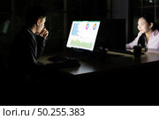 Young adult asian businessman and woman working late at night in their office with desktop computer and laptop. Using as hard working and working late concept. Стоковое фото, агентство Ingram Publishing / Фотобанк Лори