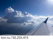 View from the window of airplane to aircraft wing on a background of blue cloudy sky and bright sun. Place for your text. Travel and tourism concept.. Wing of aircraft on a background of clear blue sky. Стоковое фото, агентство Ingram Publishing / Фотобанк Лори