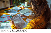 A woman is engaged in writing notes amidst a cluttered desk filled with colorful documents and highlighters during a busy evening. Стоковое AI-изображение, AI-художник Данила Большаков / Фотобанк Лори