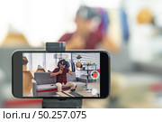 Young asian male online blogger recording live vlog video for review joystick for gaming IT product goods. Online influcencer on social media concept. Focus on mobile phone. Стоковое фото, агентство Ingram Publishing / Фотобанк Лори