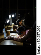Tired young asian businesswoman and businessman sleeping at computer desk in office late ay night. Стоковое фото, агентство Ingram Publishing / Фотобанк Лори