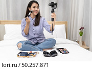 Young beautiful Asian woman beauty vlogger blogger recording live how to make up tutorial to share on social media using Gimbal Stabilizer on mobile phone. Use for vlog social media influencer concept. Стоковое фото, агентство Ingram Publishing / Фотобанк Лори