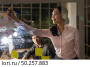 Young adult asian businessman and businesswoman meeting using whiteboard late at night in their office with desktop computer. Using as hard working and working late concept. Стоковое фото, агентство Ingram Publishing / Фотобанк Лори
