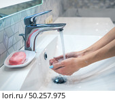 Woman is washing hands with soap and hot water at home bathroom sink. Girl is cleaning hands. Hygiene for coronavirus outbreak prevention. Covid-19 pandemic protection by washing hands frequently. Стоковое фото, агентство Ingram Publishing / Фотобанк Лори