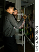 Young adult asian businessman and businesswoman meeting using whiteboard late at night in their office with desktop computer. Using as hard working and working late concept. Стоковое фото, агентство Ingram Publishing / Фотобанк Лори