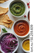 A food stylist's workspace with bowls of vibrant sauces. bright green herb pesto, deep red harissa, golden turmeric aioli arranged on beautiful modern kitchen. Стоковое AI-видео, аниматор Sergey Grishin / Фотобанк Лори