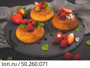 Caramel custard puddings on round slate on and dark kitchen countertop. Стоковое фото, агентство Ingram Publishing / Фотобанк Лори