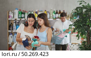 Friendly family shopping for cleaning supplies in household store. Preteen girl with mom scanning bottle of glass cleaner with smartphones while dad browsing products on shelves in background. Стоковое видео, видеограф Яков Филимонов / Фотобанк Лори