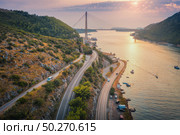 Aerial view of mountain roads  and beautiful bridge at sunset. Dubrovnik, Croatia. Top view of road, boats, yachts, green trees. Summer landscape with harbor, sea coast, highway and cloudy sky. Стоковое фото, агентство Ingram Publishing / Фотобанк Лори