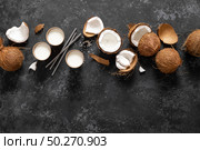 Coconut milk, whole and cracked coconuts on black background, top view. Стоковое фото, агентство Ingram Publishing / Фотобанк Лори