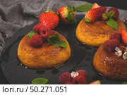 Caramel custard puddings on round slate on and dark kitchen countertop. Стоковое фото, агентство Ingram Publishing / Фотобанк Лори