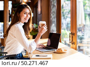 Quarantine Young asian woman wearing smart casual clothes work at home in living room using laptop and drinking hot coffee and croissant while city  lockdown for covid-19 corona virus pandemic. Стоковое фото, агентство Ingram Publishing / Фотобанк Лори