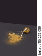Brocken antique sandglass with glass shatters and golden sand on a duotone dark background with soft shadows, copy space.. Crashed outdated hourglass with golden sand on a black duotone background. Стоковое фото, агентство Ingram Publishing / Фотобанк Лори